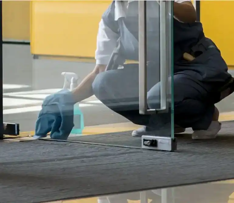 Empleado agencia de limpieza limpiando puerta vidriada